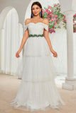 Un vestido de novia largo de tul escalonado con hombros color marfil